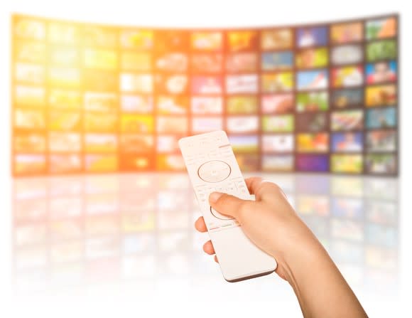 A person pointing a remote at a screen that is made up of a bunch of smaller screens.