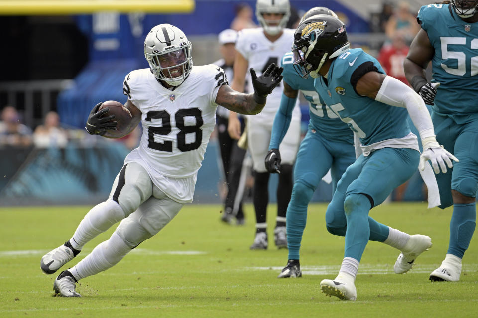 Las Vegas Raiders running back Josh Jacobs (28) tries to get past Jacksonville Jaguars safety Andre Cisco (5) in the first half of an NFL football game Sunday, Nov. 6, 2022, in Jacksonville, Fla. (AP Photo/Phelan M. Ebenhack)