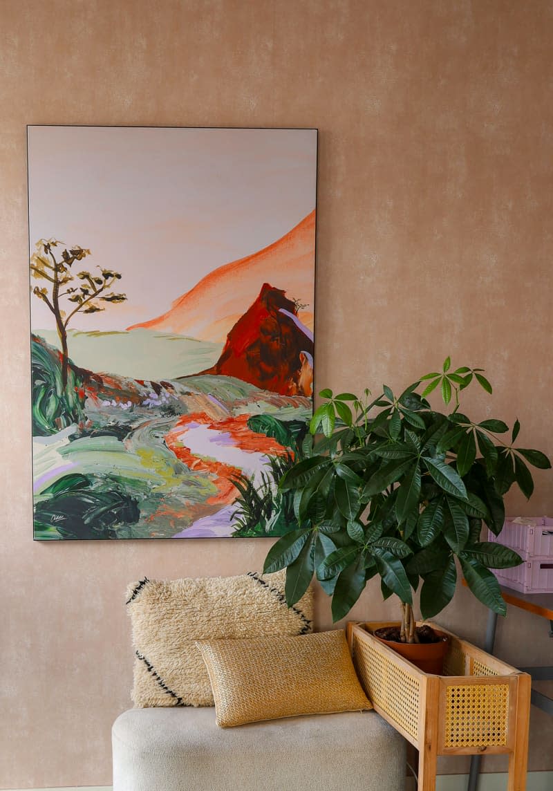 Landscape paining hung on pastel wall in office.