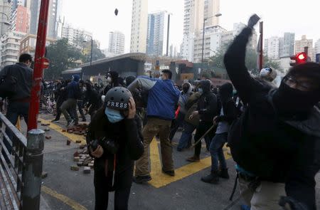 Protesters throw bricks as a journalist takes cover during a clash with riot police at Mongkok district in Hong Kong, February 9, 2016. REUTERS/Bobby Yip