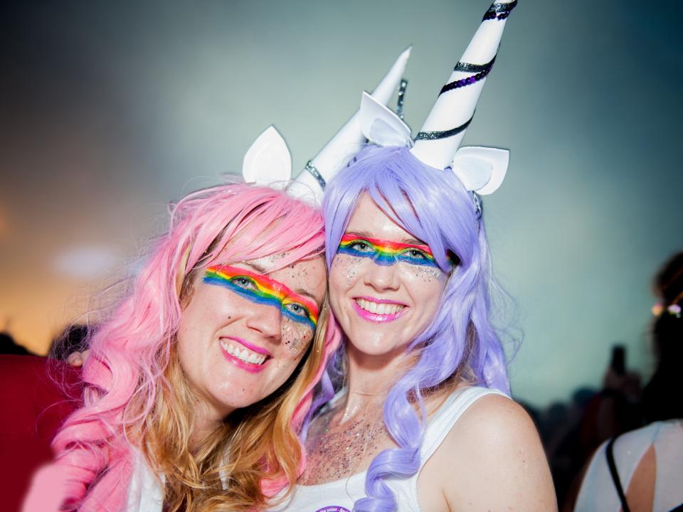 Two women at Brighton & Hove Pride in colourful unicorn costumes with pink and purple wigs