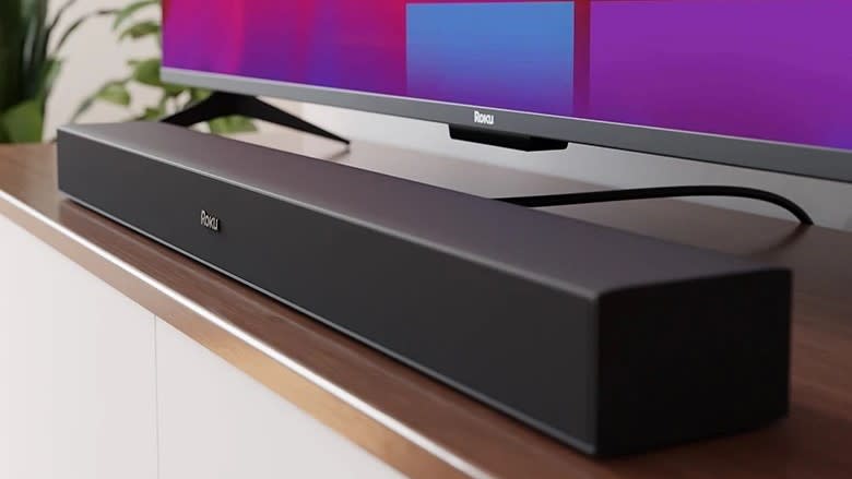  Roku TV wireless soundbar on TV stand with TV behind 