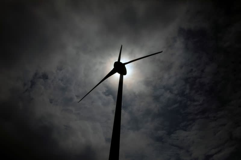 FILE PHOTO: A wind turbine is silhouetted on a mountain on the island of Evia