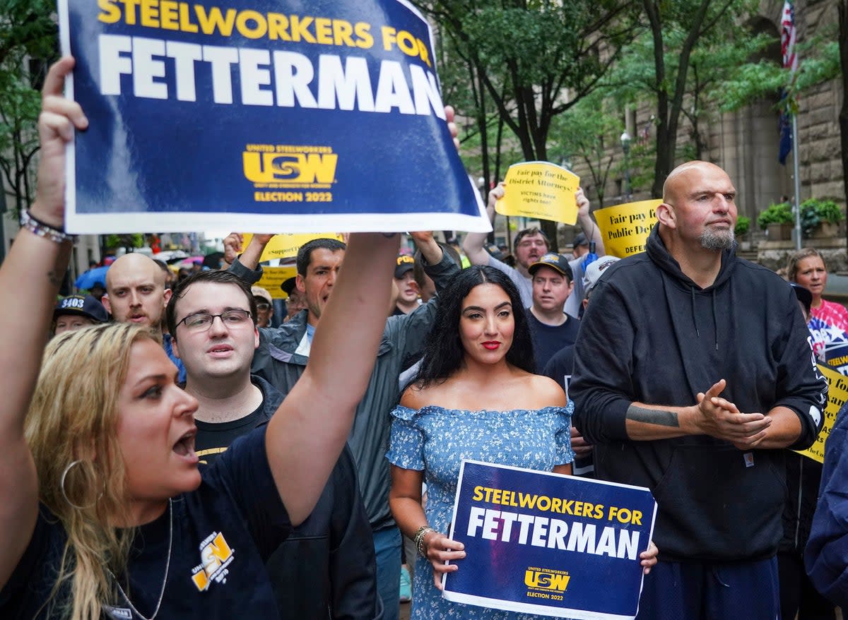 Supporters surround John Fetterman, right, Pennsylvania's Democratic lieutenant governor and senate candidate, during a Labor Day parade in downtown Pittsburgh, on 5 September. His wife, Gisele, in a blue dress holds a sign next to him (Steve Mellon/Pittsburgh Post-Gazette via AP)