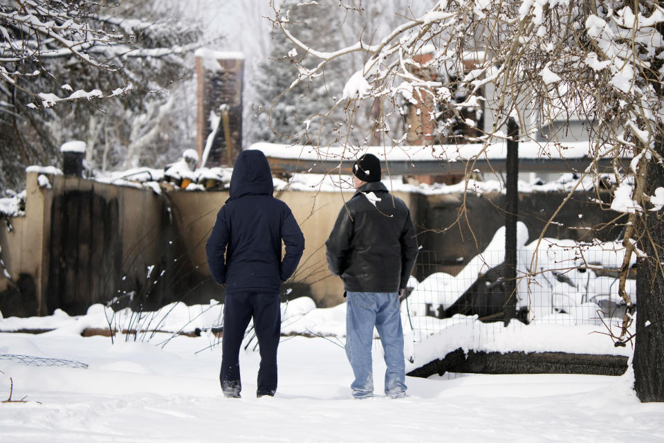 FILE - Men survey the remains of a home destroyed by a pair of wildfires, Saturday, Jan. 1, 2022, in Superior, Colo. A wildfire that destroyed nearly 1,100 homes and businesses in suburban Denver last winter caused more than $2 billion in total financial losses -- by far the costliest in Colorado history, the state insurance commissioner says. (AP Photo/David Zalubowski, File)