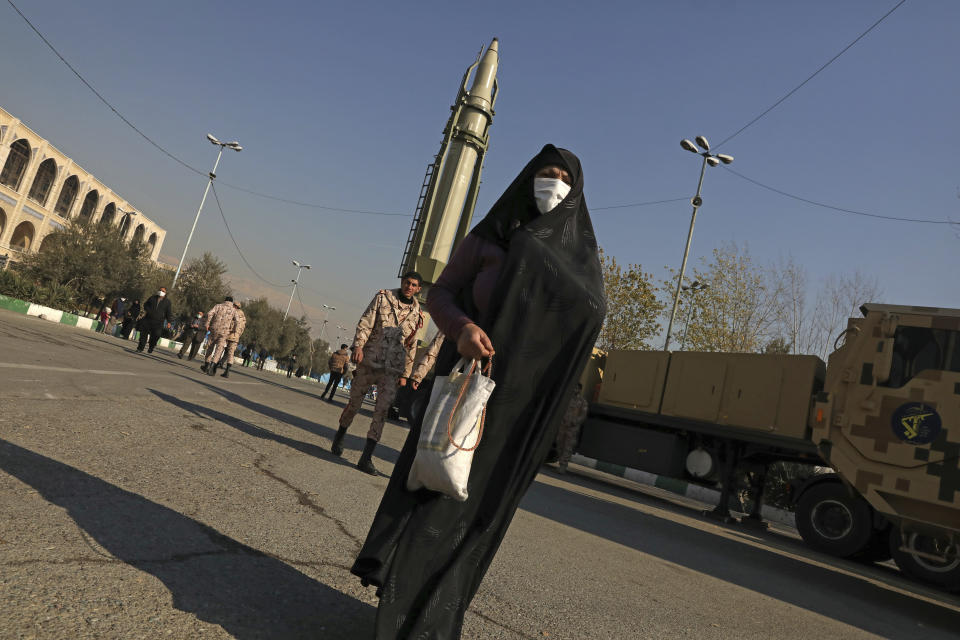 A woman walks in front of Qiam missile displayed in a missile capabilities exhibition by the paramilitary Revolutionary Guard a day prior to second anniversary of Iran's missile strike on U.S. bases in Iraq in retaliation for the U.S. drone strike that killed top Iranian general Qassem Soleimani in Baghdad, at Imam Khomeini grand mosque, in Tehran, Iran, Friday, Jan. 7, 2022. Iran put three ballistic missiles on display on Friday, as talks in Vienna aimed at reviving Tehran's nuclear deal with world powers flounder. (AP Photo/Vahid Salemi)