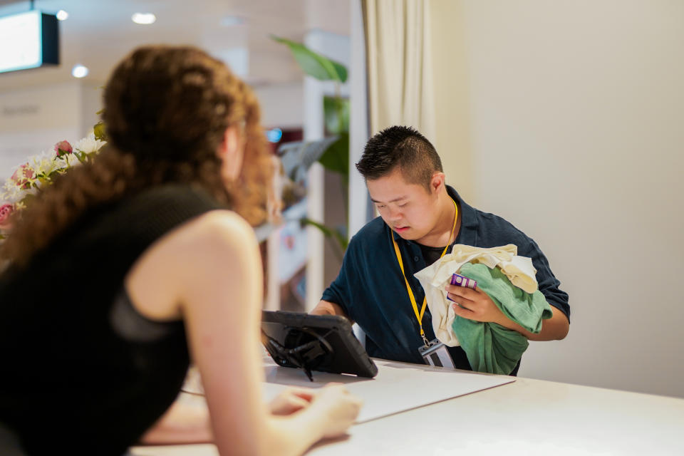 A Sales Assistant with Down's Sydnrome processes a purchase for a customer in a shop. (Business Disability Forum)