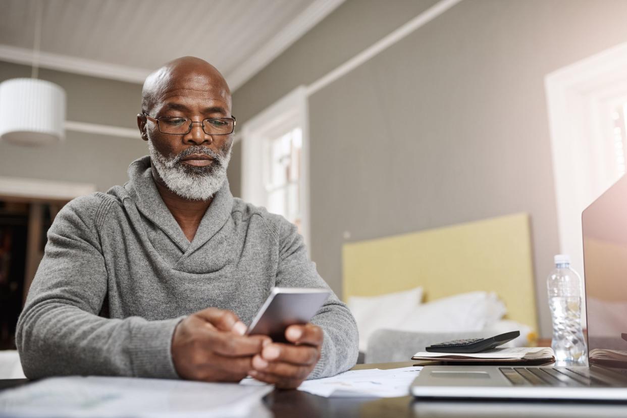 man looking at smartphone, laptop and tablet to his side