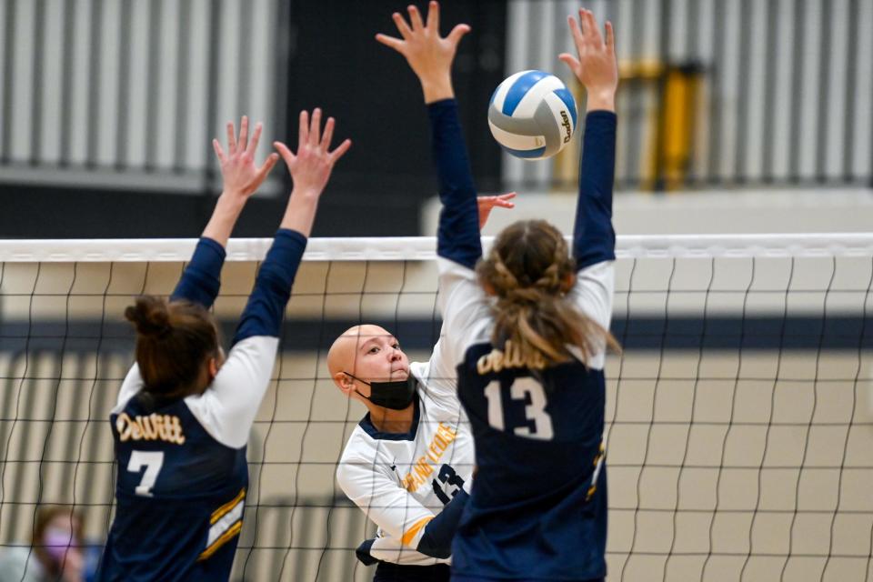 Grand Ledge's Angelia Cutts, center, spikes the ball as DeWitt Gabrielle Stafford, left, and Taya Nordman defend during the fourth set on Thursday, Nov. 4, 2021, at East Lansing High School.