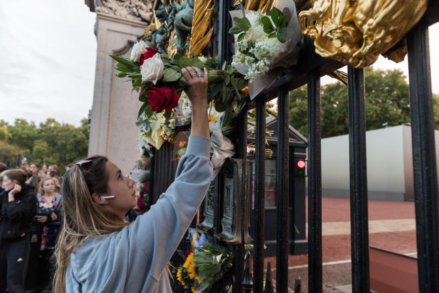 LONDON, UNITED KINGDOM - SEPTEMBER 08: A woman places a bouquet of flowers at the gate of Buckingham Palace following the announcement of the death of Queen Elizabeth II in London, United Kingdom on September 08, 2022. Buckingham Palace has announced today that Queen Elizabeth II has died peacefully at Balmoral at the age of 96. (Photo by Wiktor Szymanowicz/Anadolu Agency via Getty Images)