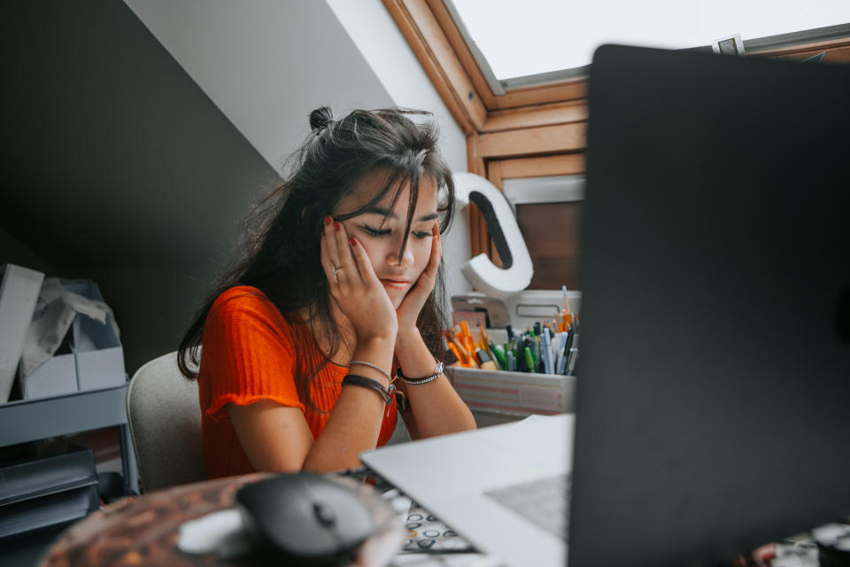 Teenager feeling stressed studying at home.