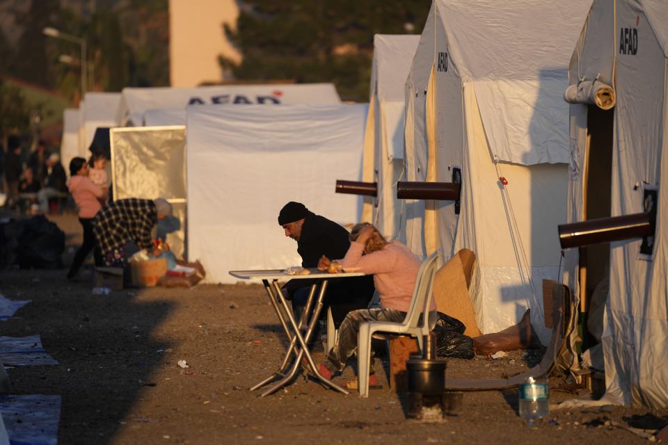 FILE - People who lost their houses in the devastating earthquake, sit outside their tent at a makeshift camp, in Iskenderun city, southern Turkey, Tuesday, Feb. 14, 2023. Hundreds of thousands of people are seeking shelter after the Feb. 6 earthquake in southern Turkey left homes unlivable. Many survivors have been unable to find tents or containers dispatched to the region by the government and aid agencies, Instead they have sought refuge in any structure that can protect them from the winter conditions, including greenhouses, rail carriages and factories. (AP Photo/Hussein Malla)