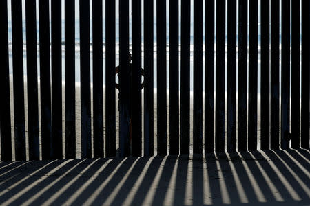 FILE PHOTO: A person looks through the border wall towards the United States at Border Field State Park in San Diego, California, U.S. November 20, 2018. REUTERS/Mike Blake/File Photo