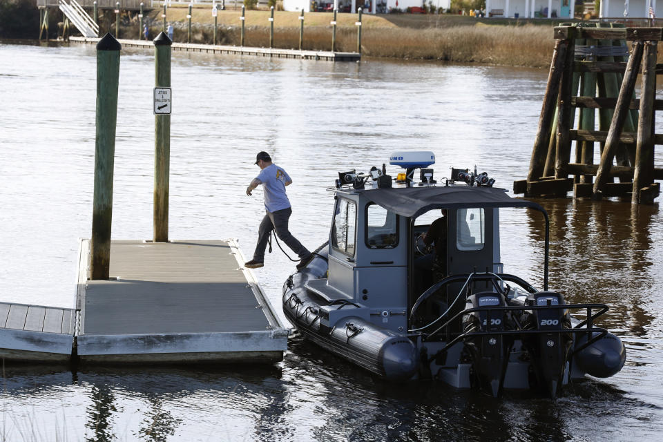A man jumps from a Navy boat to secure it to a dock on the InterCoastal Waterway in North Myrtle Beach, S.C., Tuesday, Feb. 7, 2023. Using underwater drones, warships and inflatable vessels, the Navy is carrying out an extensive operation to gather all of the pieces of the massive Chinese spy balloon a U.S. fighter jet shot down off the coast of South Carolina on Saturday. (AP Photo/Nell Redmond)