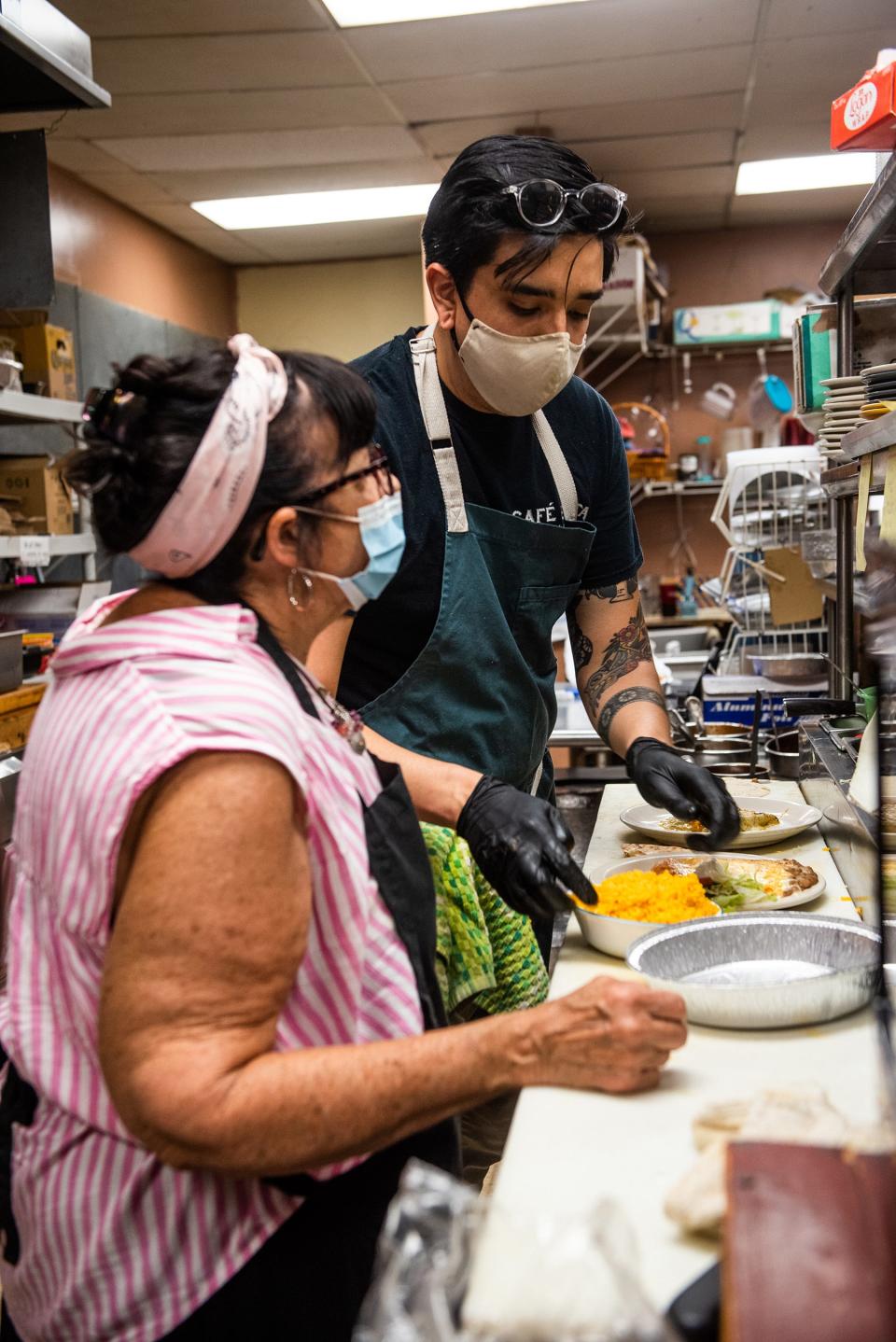 Barbara Valle, co-owner of Cafe Fiesta in Woodbury, left, and her son Carlos Valle, right, prepare meals for customers in the kitchen.