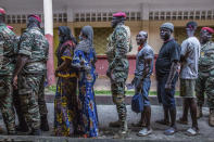 Civilians and soldiers line up to vote at the Boulbinet Deaf School in Conakry, Guinea, Sunday Oct. 18, 2020. Guinean President Alpha Conde is seeking to extend his decade in power, facing off against his longtime rival Cellou Dalein Diallo for the third time at the polls. (AP Photo/Sadak Souici)