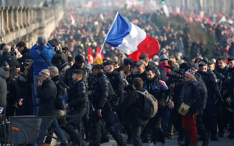 French labour unions and workers on strike hold a French flag in Paris  - Credit: FRANCOIS LENOIR&nbsp;/Reuters