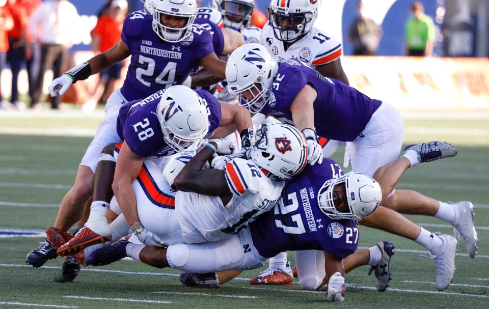 Linebacker Bryce Gallagher (32), defensive back Rod Heard (24) and their Northwestern teammates tackle Auburn Tigers durning the Citrus Bowl on Jan. 1, 2021.