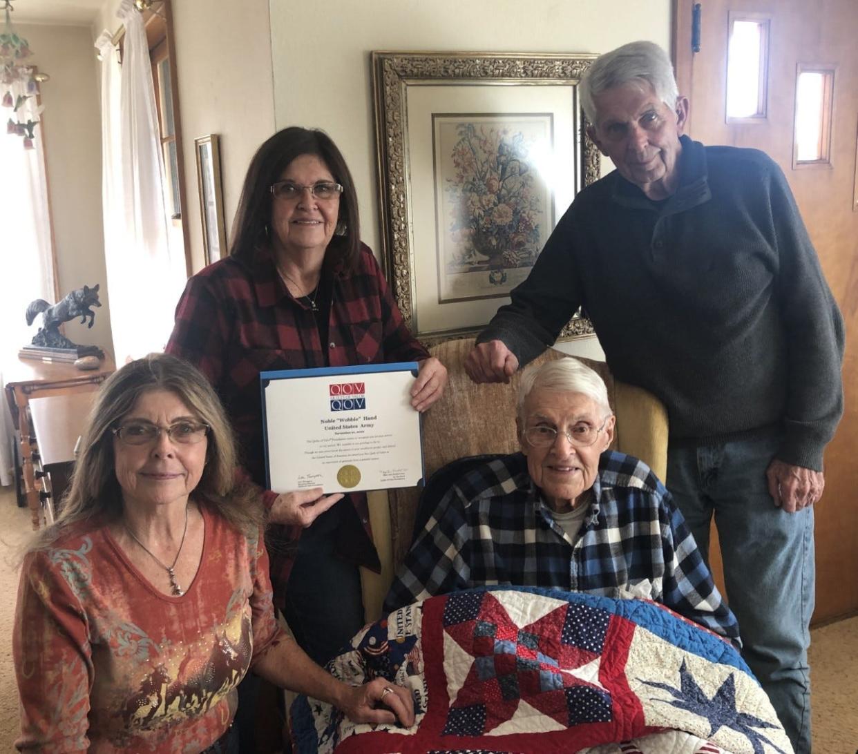 Barbara Green, left, Sheila Schrader and Rick Hand join their father, Noble Hand, for the presentation of the World War II veteran's Quilt of Valor.