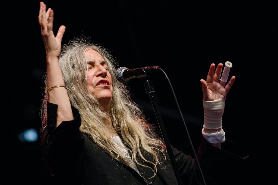 Patti Smith performing behind a microphone with long grey hair