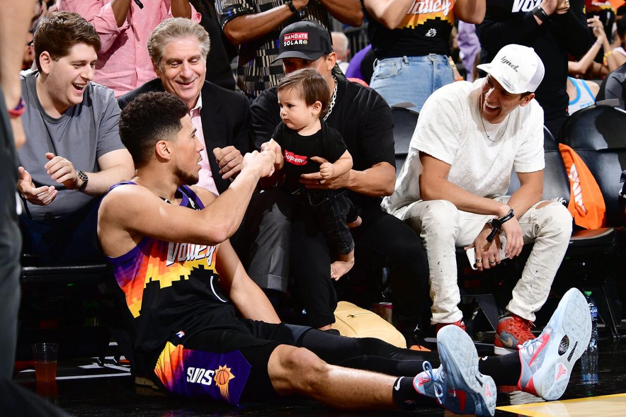 Devin Booker #1 of the Phoenix Suns high fives a fan during Round 1 Game 2 of the 2022 NBA Playoffs on April 19, 2022 at Footprint Center in Phoenix, Arizona.