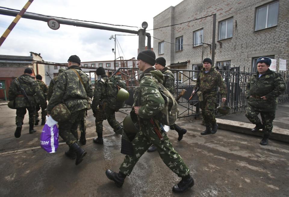 Soldiers walk near the armory of the Ukrainian army in the village of Poraskoveyevka, eastern Ukraine, Thursday, March 20, 2014. The disheveled men barricading the muddy lane leading into a military base in this eastern Ukraine village say they're taking a stand to defend Russian-speakers. (AP Photo/Sergei Grits)