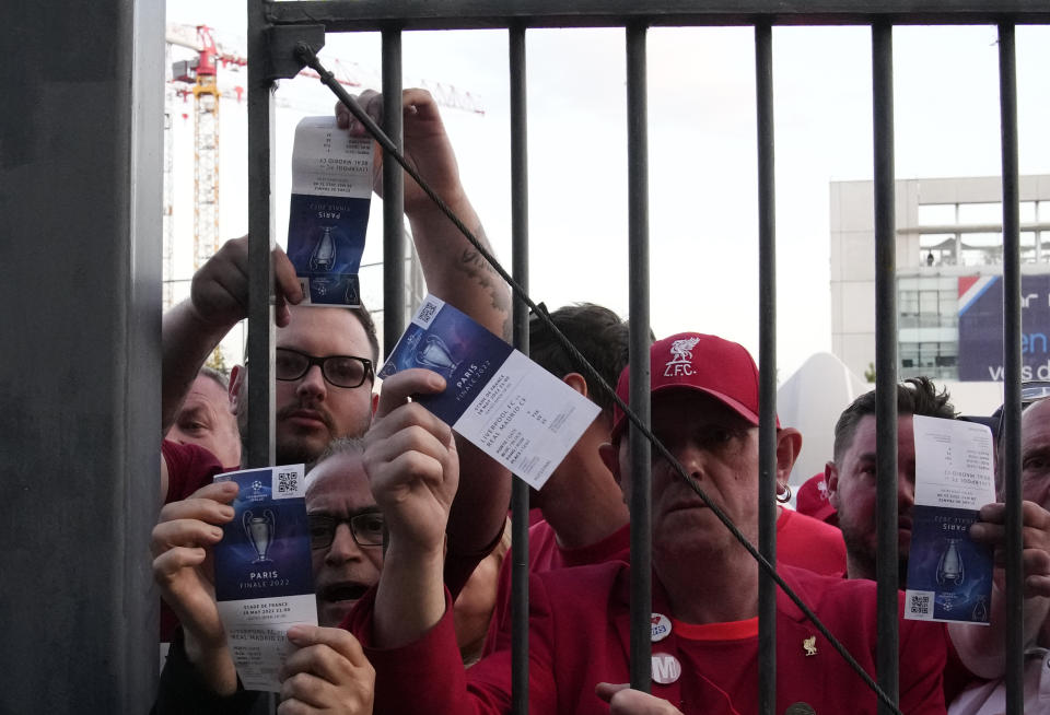 Fans shows tickets in front of the Stade de France prior the Champions League final soccer match between Liverpool and Real Madrid, in Saint Denis near Paris, Saturday, May 28, 2022. Police have deployed tear gas on supporters waiting in long lines to get into the Stade de France for the Champions League final between Liverpool and Real Madrid that was delayed by 37 minutes while security struggled to cope with the vast crowd and fans climbing over fences. (AP Photo/Christophe Ena)