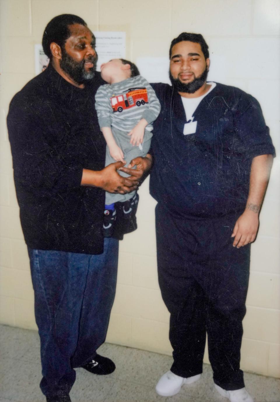 A snapshot shows Melvin Spivey, left, on a visit with his grandson Donovann Hall at the Adult Correctional Institutions. Spivey is holding Hall's son, J-ayden, now age 10 .