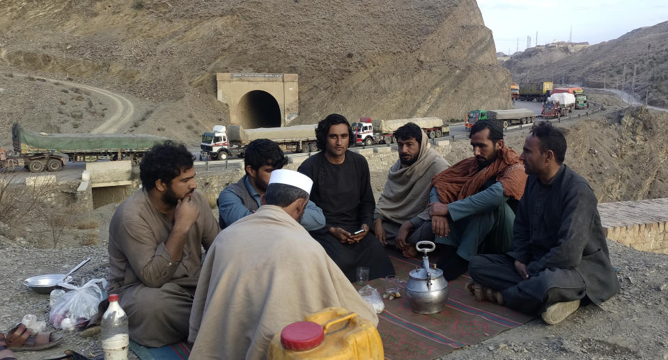 Drivers drink green tea close to their stranded trucks loaded with supplies for Afghanistan, line up on a highway as they wait to open the Torkham crossing point, which was closed by Afghan Taliban rulers, in Landi Kotal, an area Pakistan's district Khyber along Afghan border, Tuesday, Feb. 21, 2023. The main crossing on the Afghan-Pakistan border remained shut Tuesday for the third straight day, officials said, after Afghanistan's Taliban rulers earlier this week closed the key trade route and exchanged fire with Pakistani border guards. (AP Photo/Qazi Rauf)