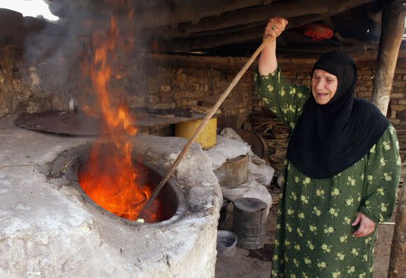 An Iraqi woman bakes bread using a mud stove  in Baghdad in 2006.