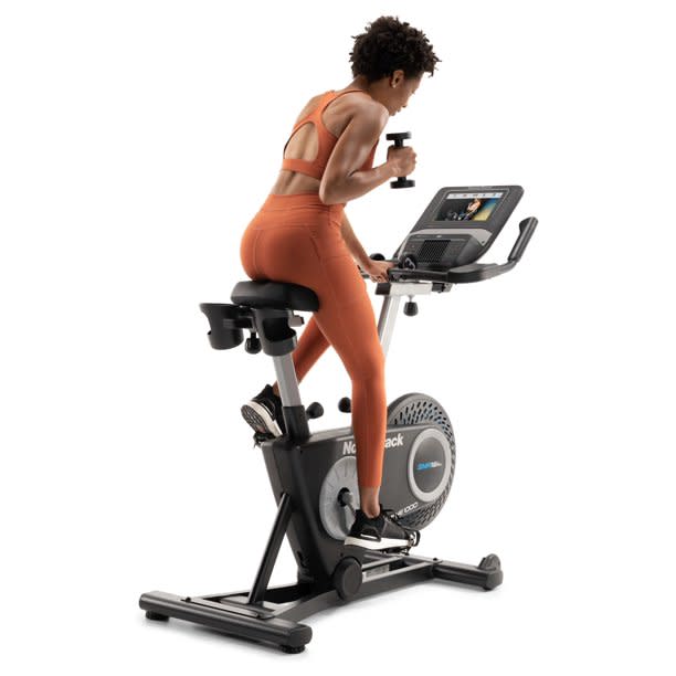 Woman on stationary bike holding a weight. (Photo: Walmart)