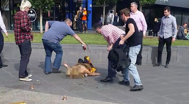 A man pours a can of drink over the street performer. Source: Herald Sun