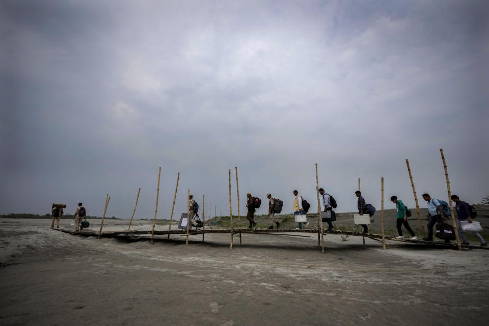 Polling officials walk on the sand to cross the dried river Brahmaputra on the eve of parliament election at Baghmora Chapori (small island) of Majuli, India, April 18, 2024. (AP Photo/Anupam Nath)