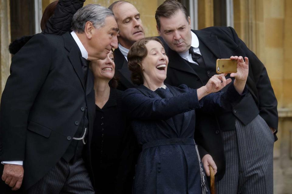 Jim Carter, Raquel Cassidy, Kevin Doyle, Phyllis Logan, and Brendan Coyle taking a selfie with an iphone on the set of downton abbey