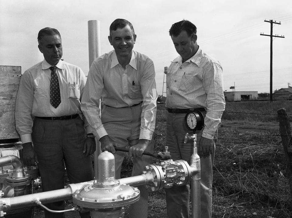 Sept 27, 1950: James M. Noah, Roanoke merchant, center, was named by Mayor C. W. Fanning to turn on the gas for Roanoke. At left is Jack Cherry, district foreman for Lone Star Gas Company at Grand Prairie, and at right, Charlie Wheeler, sub district manager at Grapevine.