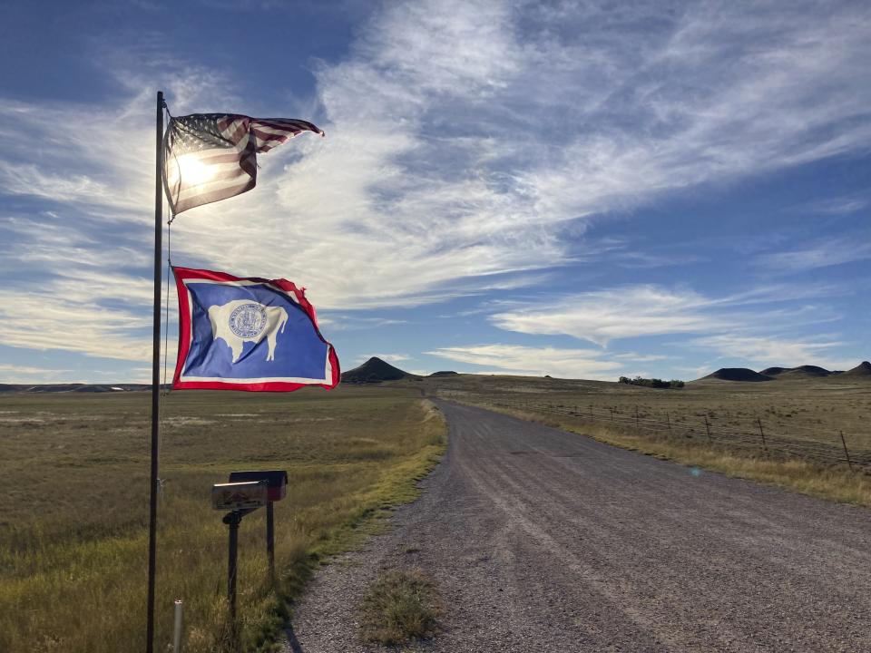 The U.S. and Wyoming flags flutter in the wind next to a rural road south of Gillette, Wyo., on Wednesday, Sept. 22, 2021. Wyoming has the lowest COVID-19 vaccination rate in the U.S. and the Gillette area has one of the lowest rates in Wyoming. (AP Photo/Mead Gruver)