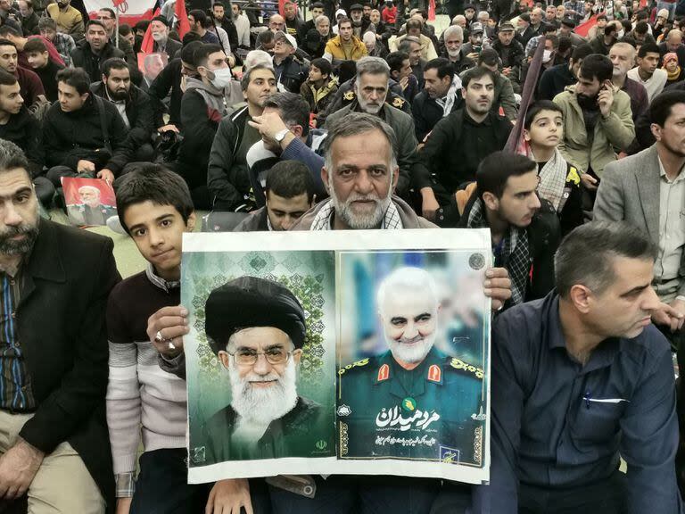 Un hombre sostiene retratos del líder supremo Ayatolá Ali Jamenei y del fallecido comandante iraní de alto rango Qasem Soleimani durante las ceremonias que conmemoran el aniversario de su asesinato en la capital iraní, Teherán, el 3 de enero de 2024. 