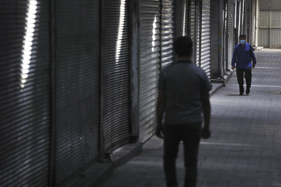 People walk through closed Tehran's Grand Bazaar, Iran, Saturday, April 10, 2021. Iran on Saturday imposed partial lockdown on businesses in major shopping centers as well as intercity travels through personal cars in major cities including capital Tehran as it struggles with the worst outbreak of the coronavirus in the Mideast region. (AP Photo/Vahid Salemi)