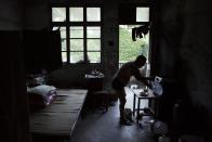 Sun Ayue, one of very few residents of the abandoned fishing village of Houtouwan on the island of Shengshan prepares dinner at the room where he lives July 25, 2015. (REUTERS/Damir Sagolj)