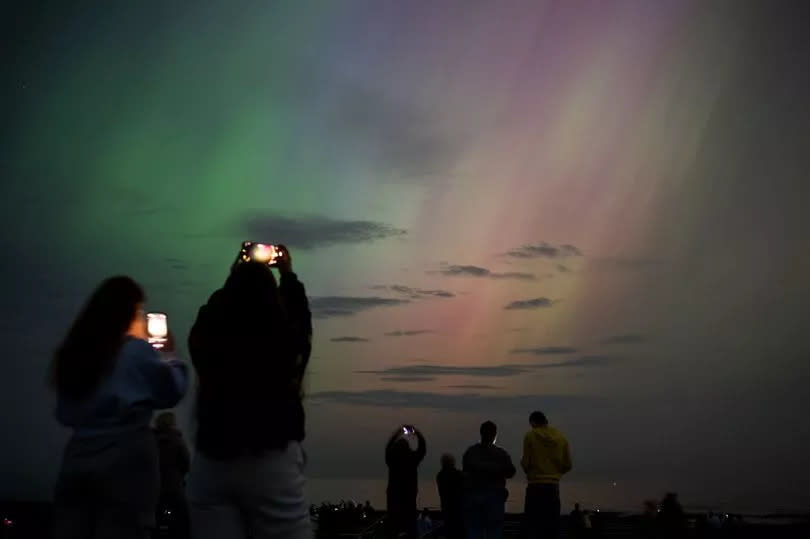 People visit St Mary's lighthouse in Whitley Bay to see the aurora borealis, commonly known as the northern lights, on May 10, 2024 in Whitley Bay, England. The UK met office said a strong solar storm may allow northern parts of the UK the chance to see displays of aurora