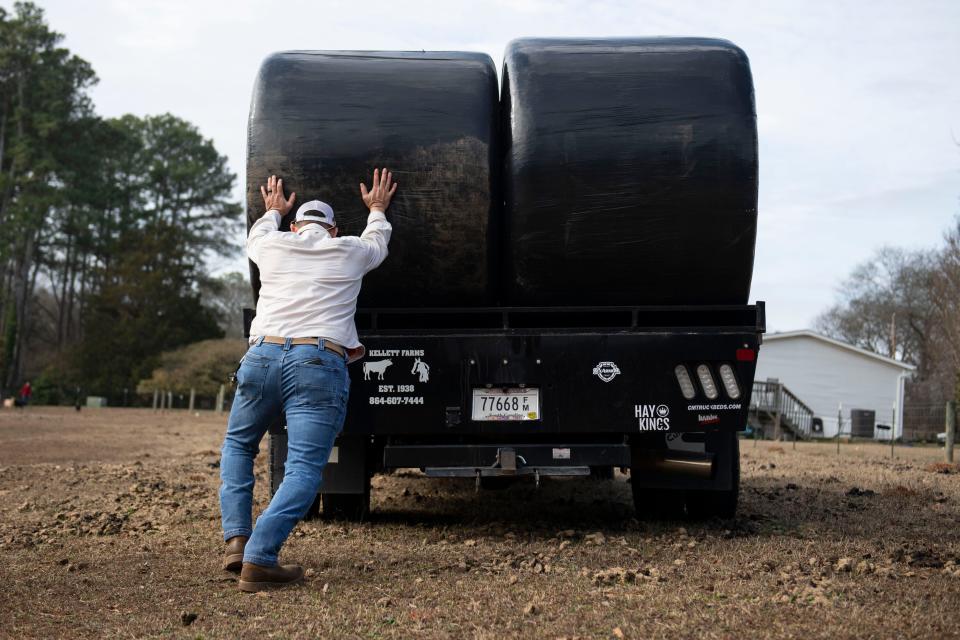 Allen Kellett, third-generation farmer and owner of Kellett Farms, unloads bales of hay from his truck for a client on Saturday, Feb. 10, 2024.