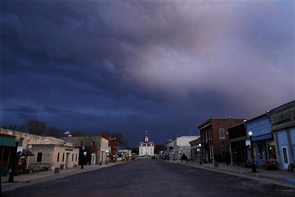 A deserted street leads to the historic Chase County Courthouse at dusk Thursday, April 23, 2020, in Cottonwood Falls, Kan. (AP Photo/Charlie Riedel)