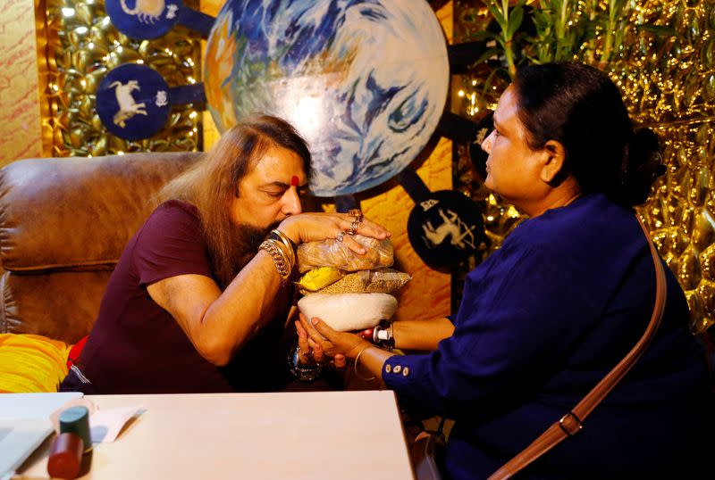 Sanjay Sharma, a mystic healer and astrologer, making prayers as he hold herbs in his hands before giving them to Anju Devi at his office, amidst the spread of the coronavirus disease (COVID-19), in New Delhi