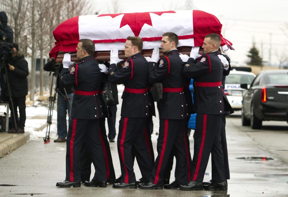 The casket of police constable John Zivcic is carried by honor guard into the public memorial in Toronto