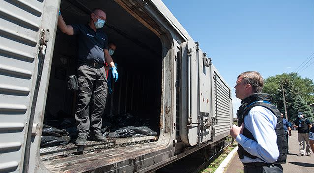 Deputy head of the OSCE mission to Ukraine Alexander Hug, right, speaks to a member of Netherlands' National Forensic Investigations team on the platform as a refrigerated train loaded with bodies of the passengers departs the station in Torez, eastern Ukraine. Photo: AP.