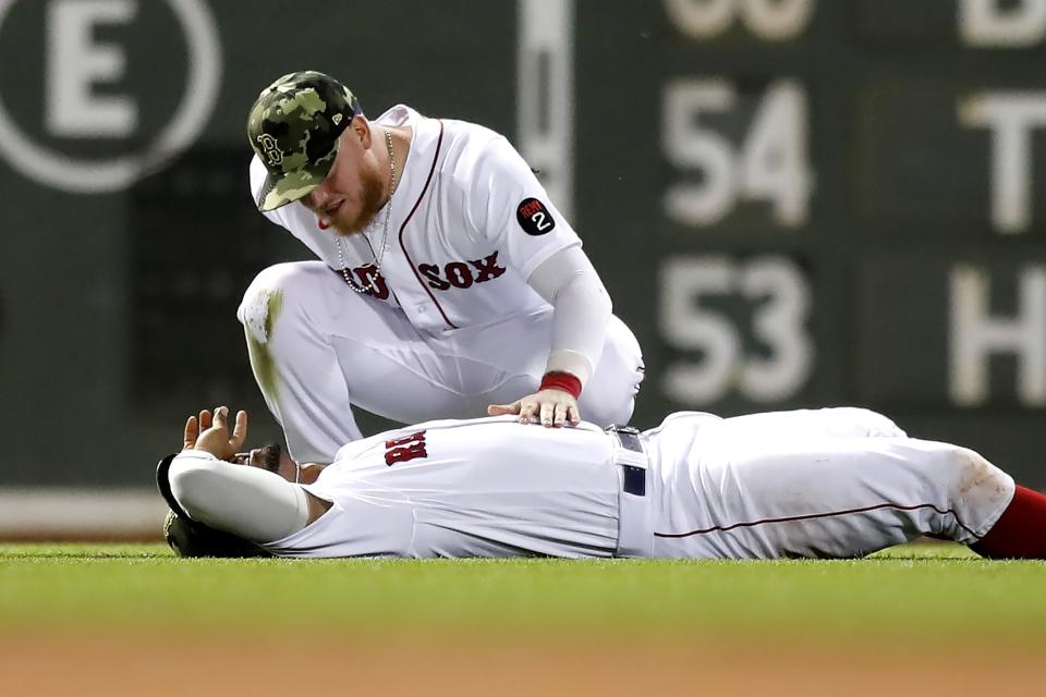 Boston Red Sox's Alex Verdugo, top, checks on Xander Bogaerts after they collided while trying to catch a a ball hit by Seattle Mariners' J.P. Crawford during the eighth inning of a baseball game Friday, May 20, 2022, in Boston. Crawford reached on the error, and advanced to second. (AP Photo/Michael Dwyer)