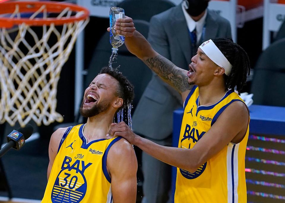 Golden State Warriors guard Damion Lee, right, pours water over the head of guard Stephen Curry (30) while celebrating Curry's career-high 62 points against the Portland Trail Blazers in an NBA basketball game in San Francisco, Sunday, Jan. 3, 2021. (AP Photo/Tony Avelar)