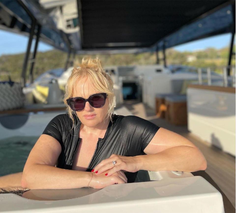 Rebel Wilson in a black swimsuit on a yacht. 