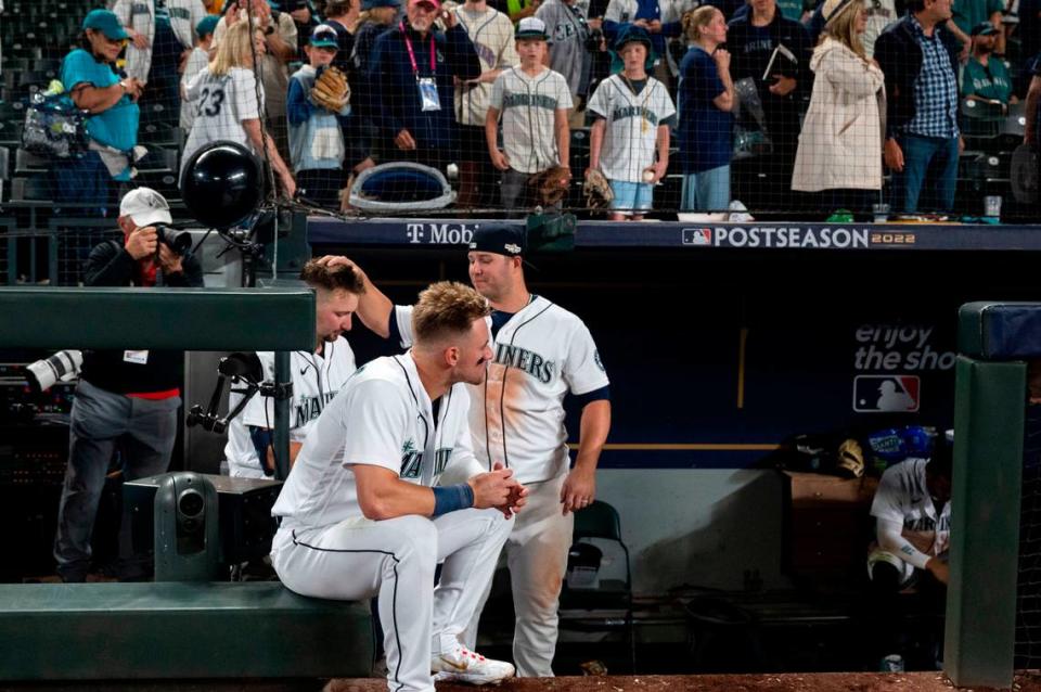 Seattle Mariners first baseman Ty France (23) consoles catcher Cal Raleigh (29) as he and Jarred Kelenic sit on the edge of the dugout watching the Astros players celebrate their 1-0 win in 18 innings of game 3 of the ALDS on Saturday, Oct. 15, 2022, at T-Mobile Park in Seattle.