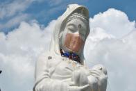 Workers place a mask on a 57-metre-high statue of Buddhist goddess Kannon to pray for the end of the coronavirus disease (COVID-19) pandemic at Houkokuji Aizu Betsuin temple in Aizuwakamatsu, Fukushima Prefecture, Japan